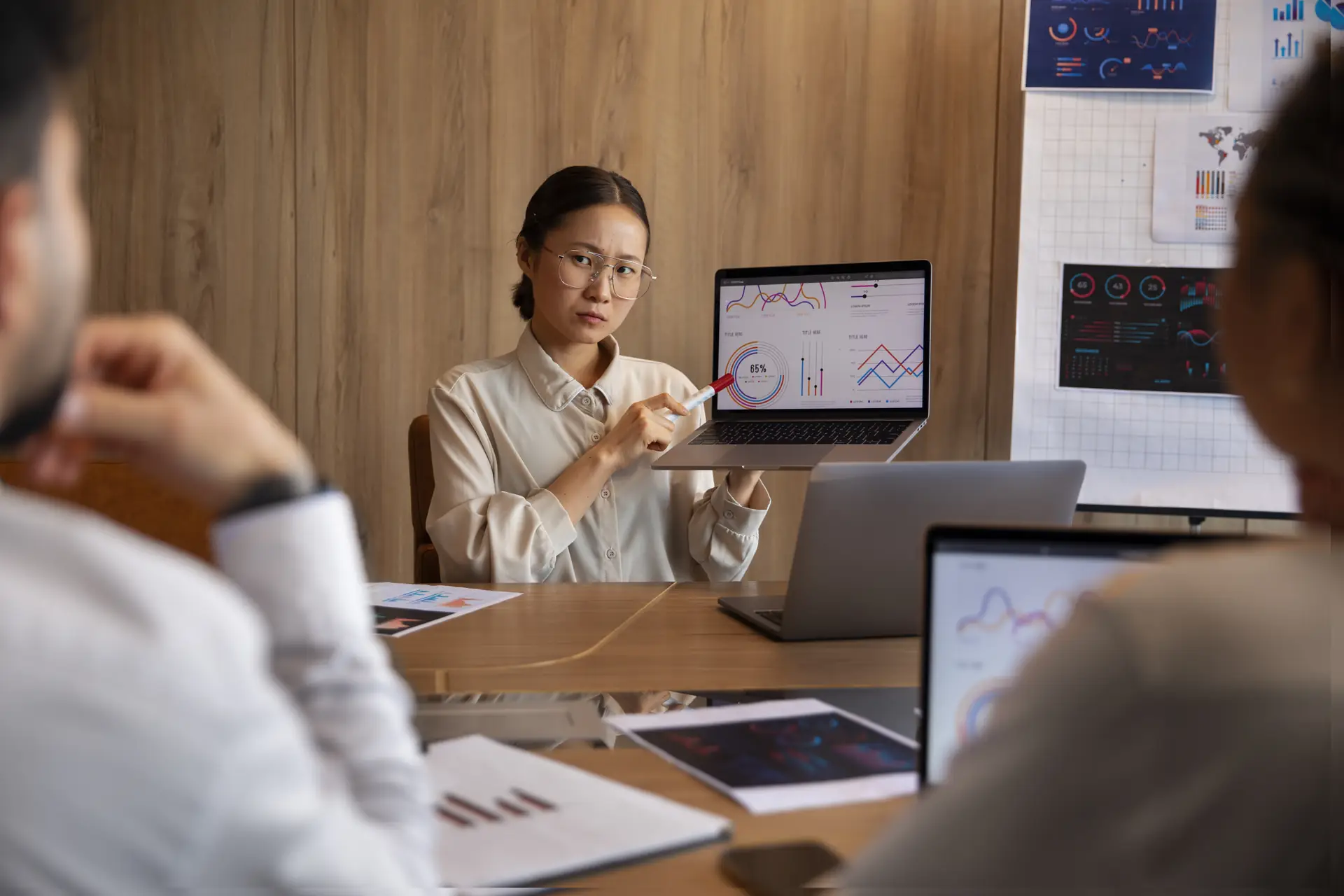 People around a meeting table discussing charts shown on laptops